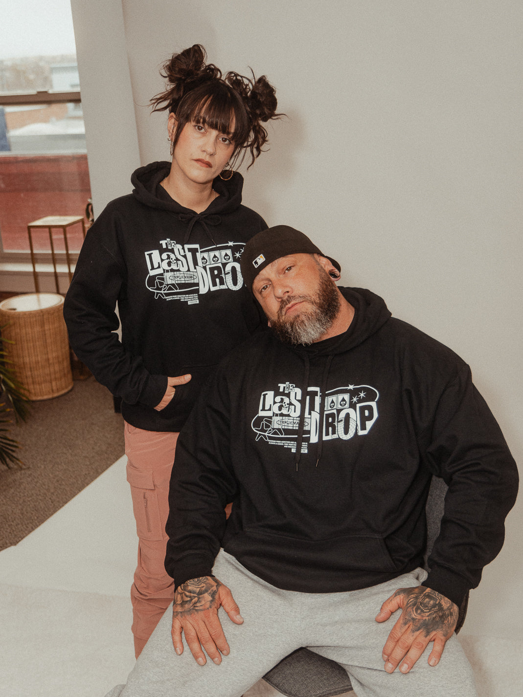 A man and woman posing for a photo in a black hoodie with a Y2K design.