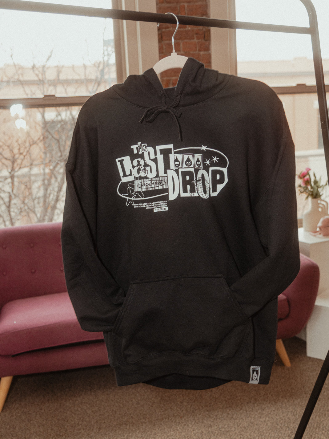 A Trademark Black Y2K Hoodie hangs on a rack in a living room, exuding comfort and style.